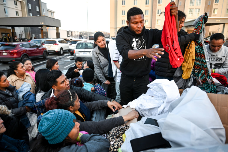 Jeison Hurdado Pulgarin hands out donated clothes to a group Venezuelan migrants in a parking lot outside