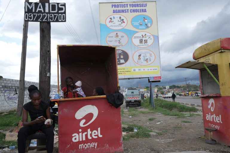 Street vendors sell phone cards under a billboard urging people to protect themselves from Cholera in Lusaka, Zambia,