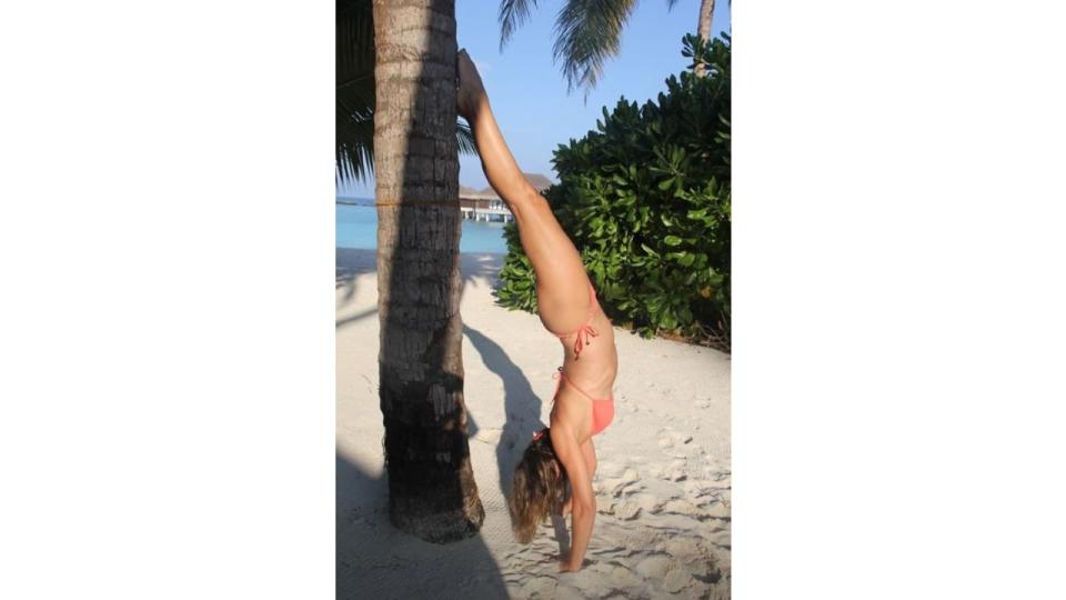 Elizabeth Hurley doing a handstand up against a palm tree