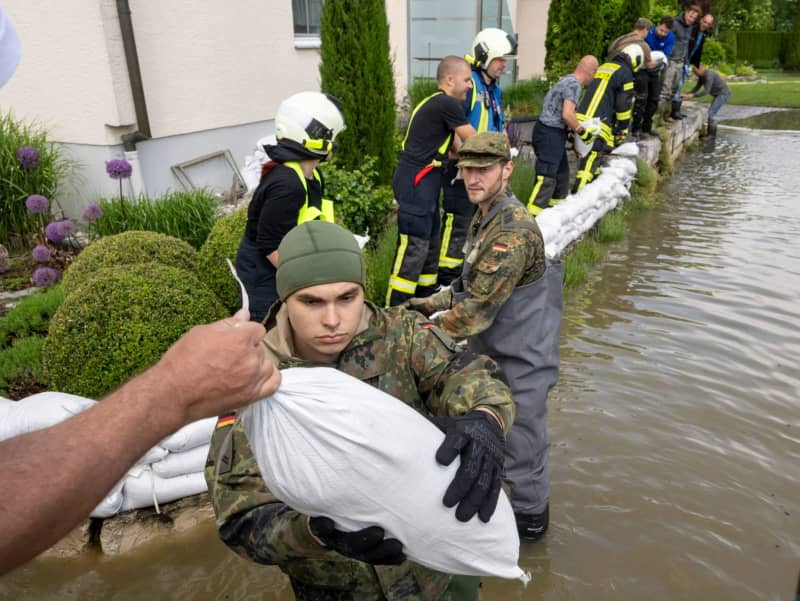 Soldiers from the German Armed Forces build a barrier of sandbags together with civilian firefighters. Stefan Puchner/dpa