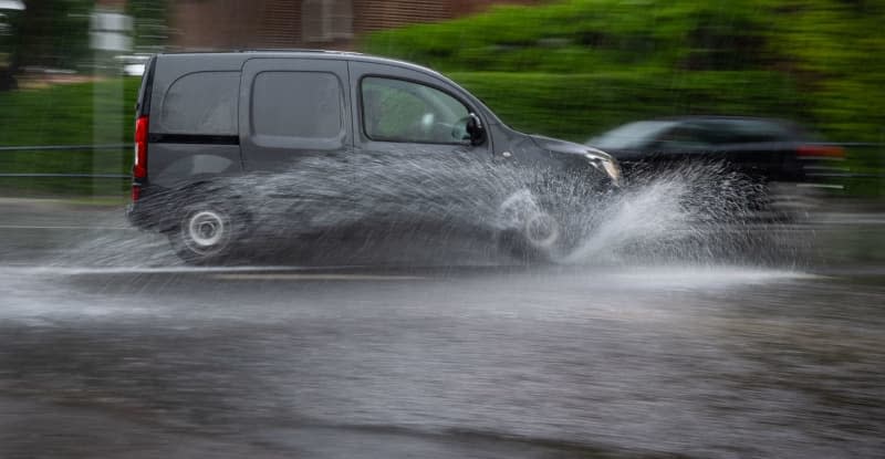 A car drives across a flooded intersection during a thunderstorm with heavy rain. Monika Skolimowska/dpa