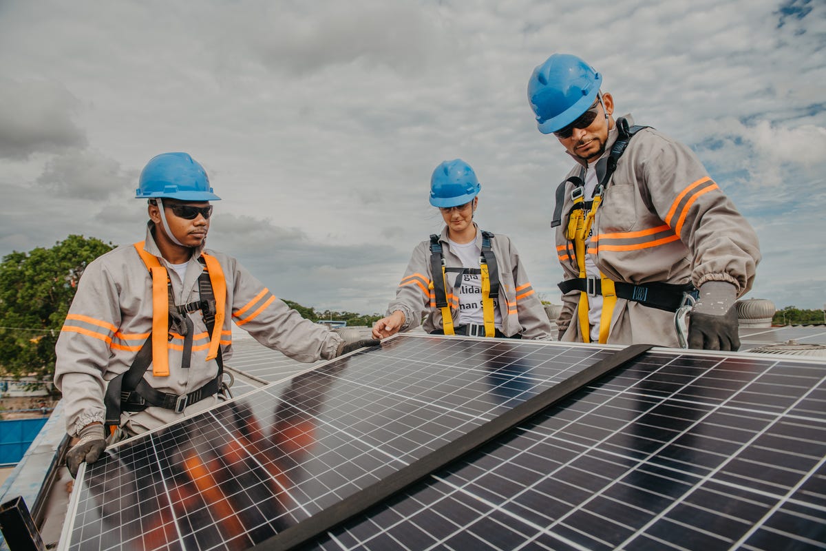 Three people installing a solar panel
