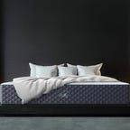 puffy lux memory foam mattress against a dark wall.