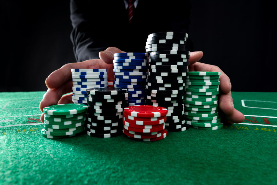 Person at a poker table with large stacks of poker chips