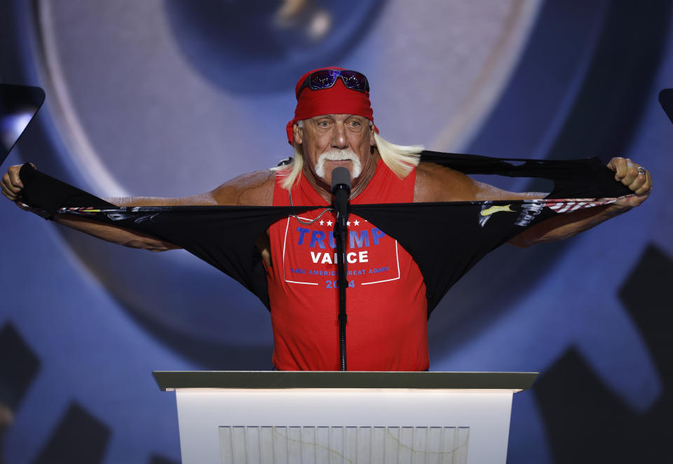 Hulk Hogan tearing a shirt while standing at a podium, wearing a red bandana, sunglasses, and a sleeveless "Trump Pence" shirt