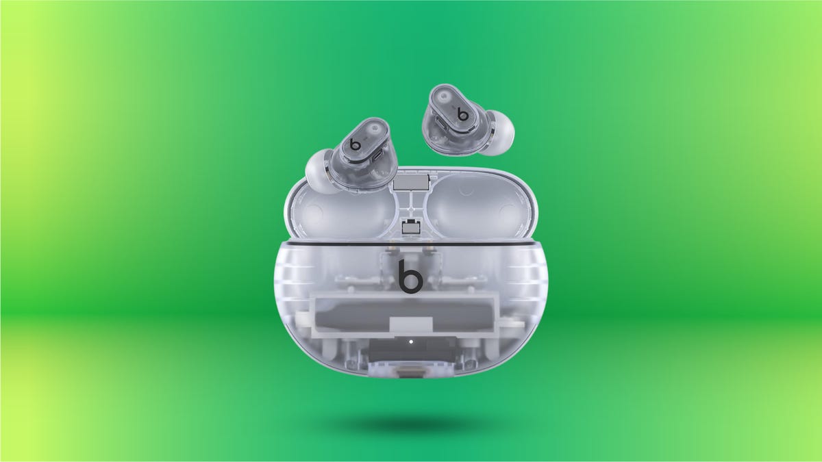 Beats Studio Buds Plus in transparent color option on display on green background image.