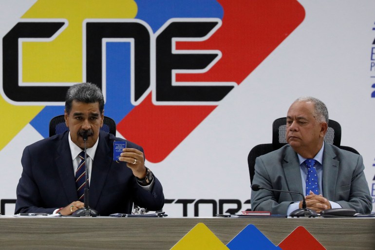 Nicolas Maduro sits next to the head of Venezuela's electoral authority Elvis Amoroso