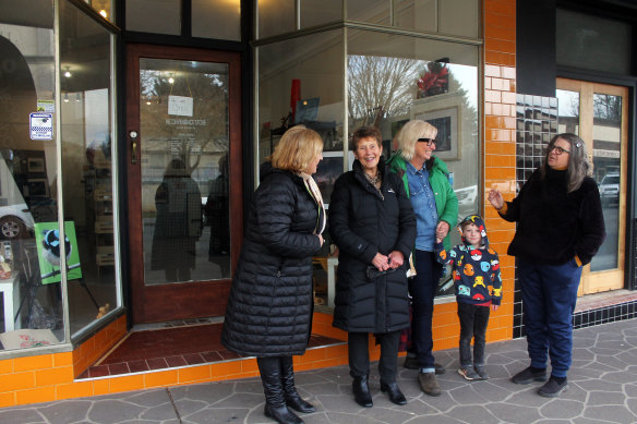 Margaret Sedgwick, second from left, meets with fellow Batlow locals outside the Inconvenience Store, she helped set up, on Pioneer Street.