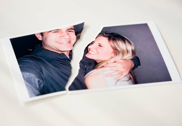 A torn photograph of a smiling couple embracing, symbolizing a breakup