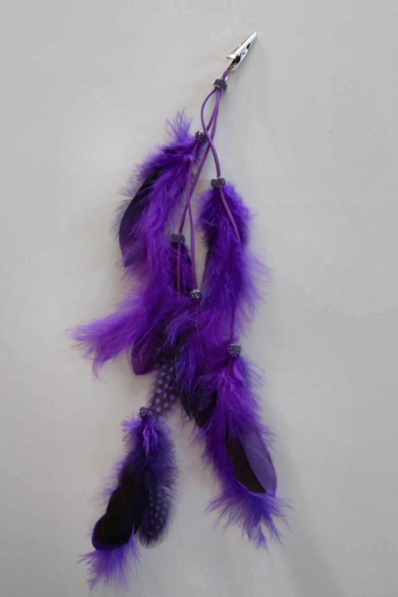 Hair clip accessory with purple feathers hanging from strings
