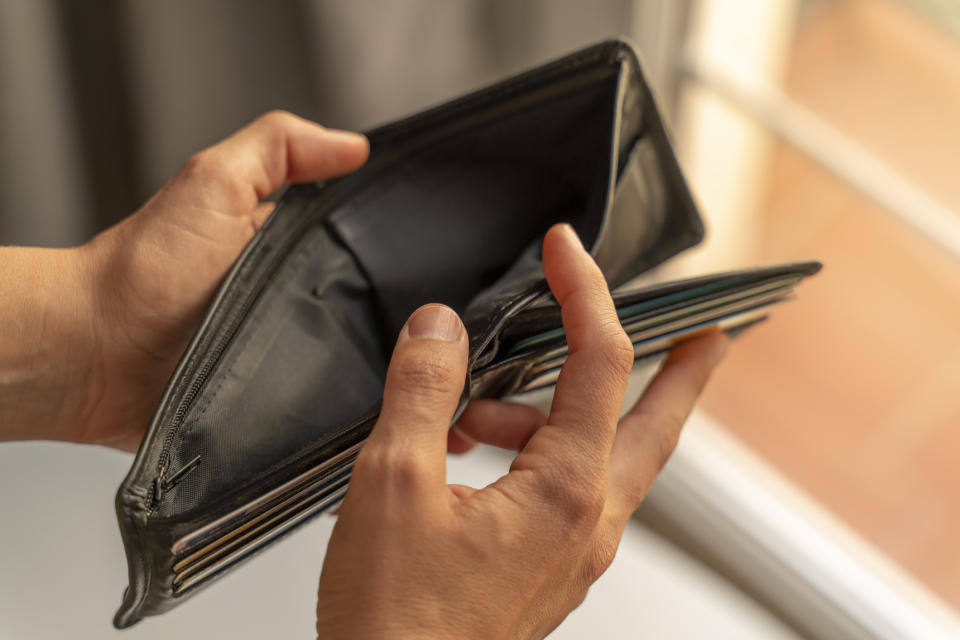 Person holding an open, empty wallet with multiple card slots visible