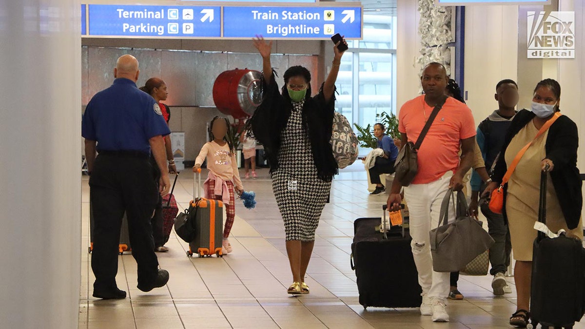 Sharitta Grier walks through the airport with arms raised