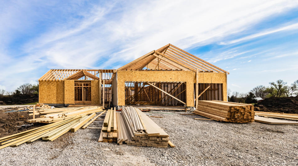 A partially constructed house with wooden frames and various building materials scattered around in a construction site