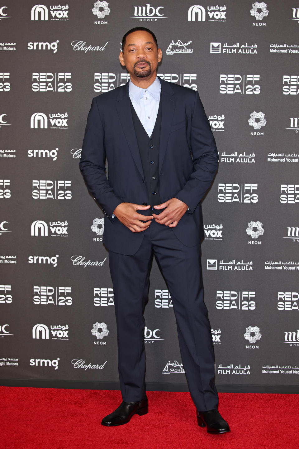 Will Smith stands on the red carpet in a three-piece suit at the Red Sea International Film Festival