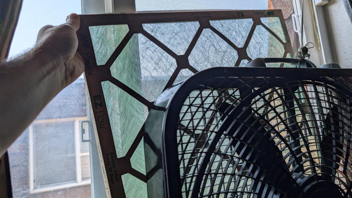 bedroom window fan with hand holding air filter
