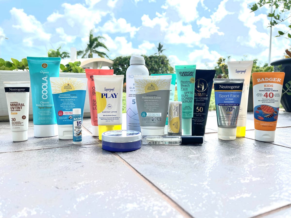 Different sunscreens from different brands in front of a sunny background.