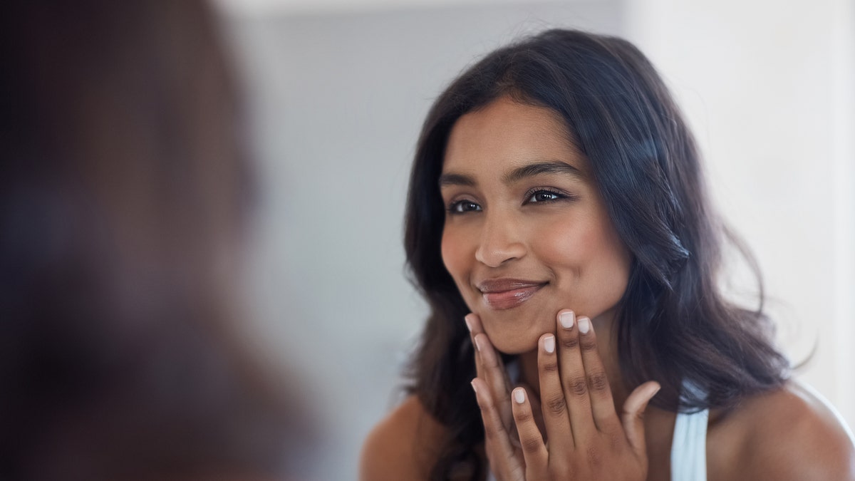 Woman looking at face in the mirror