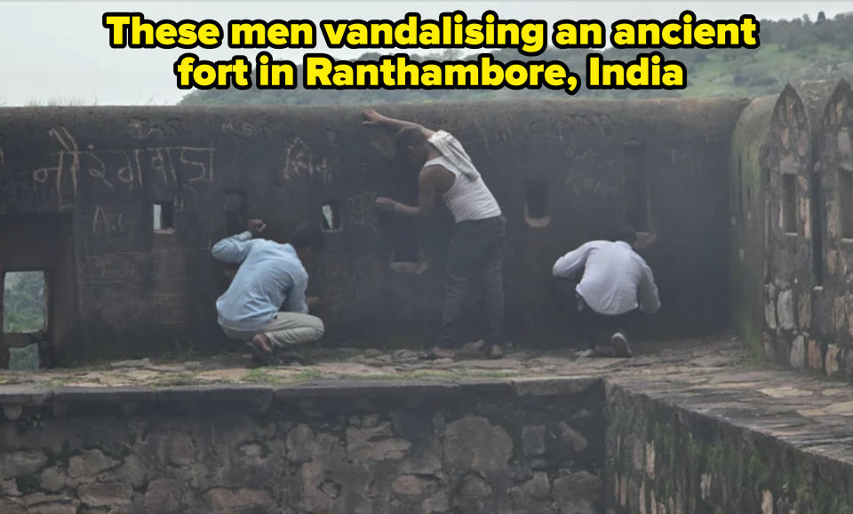 Three people looking through and leaning against the walls of an old fort. Graffiti is visible on the walls