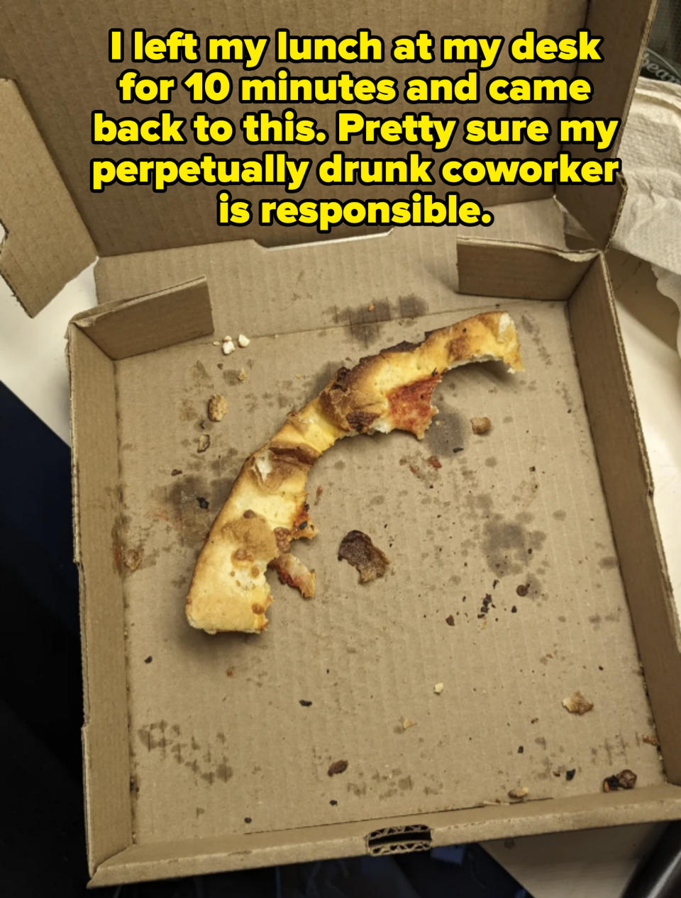 A nearly empty pizza box with only one slice of pizza crust and various crumbs remaining inside