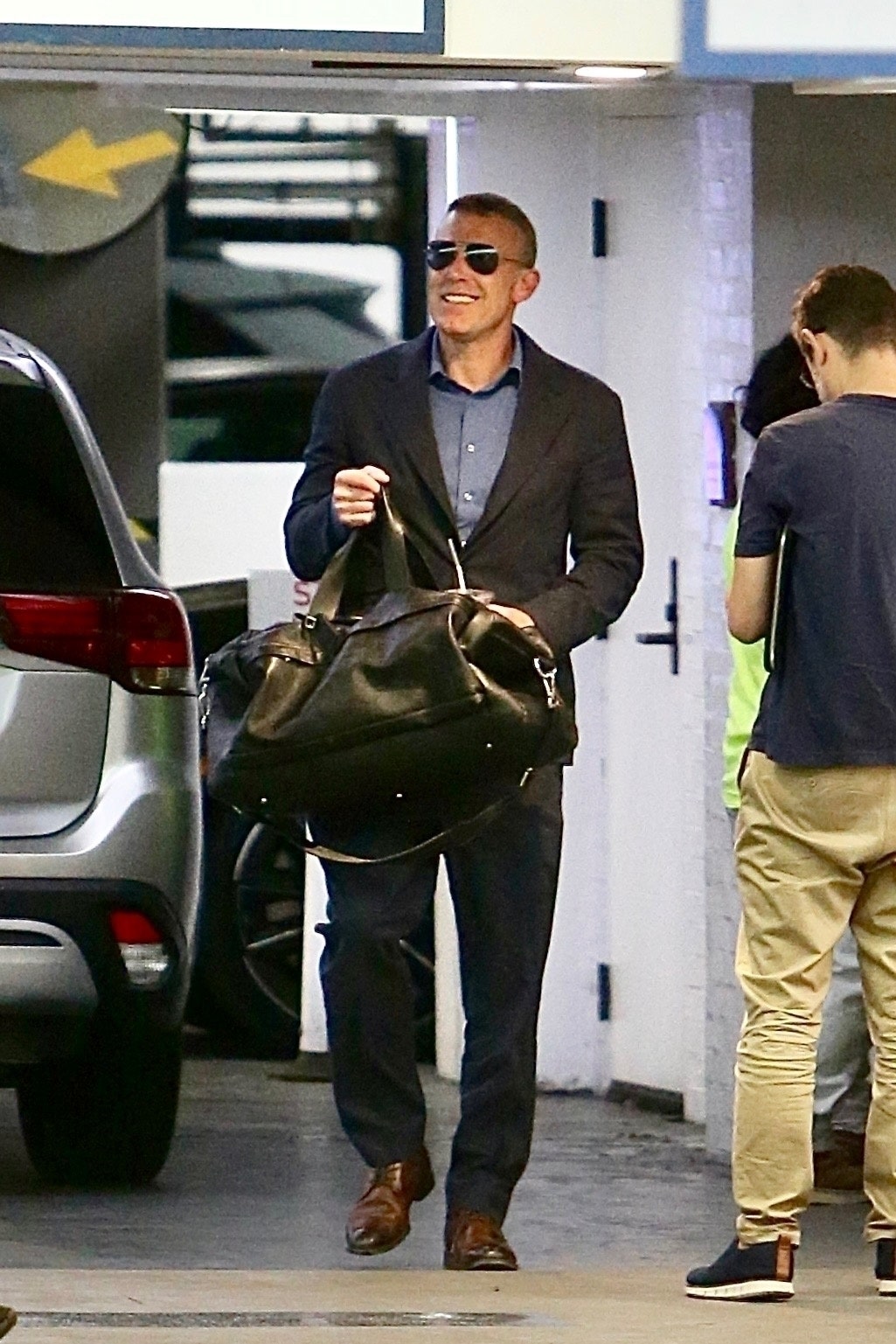 Image may contain Accessories Bag Handbag Clothing Formal Wear Suit Pedestrian Person Adult Blazer and Coat