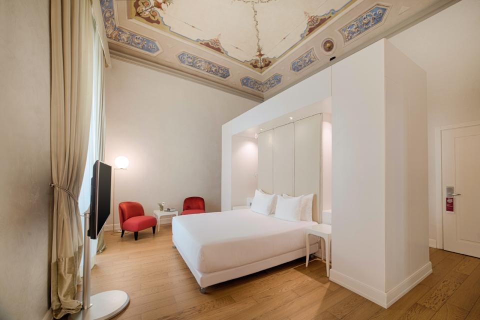 A junior suite with frescoes on the ceiling at Italy’s oldest hotel NH Collection Firenze Porta Rossa in Florence.