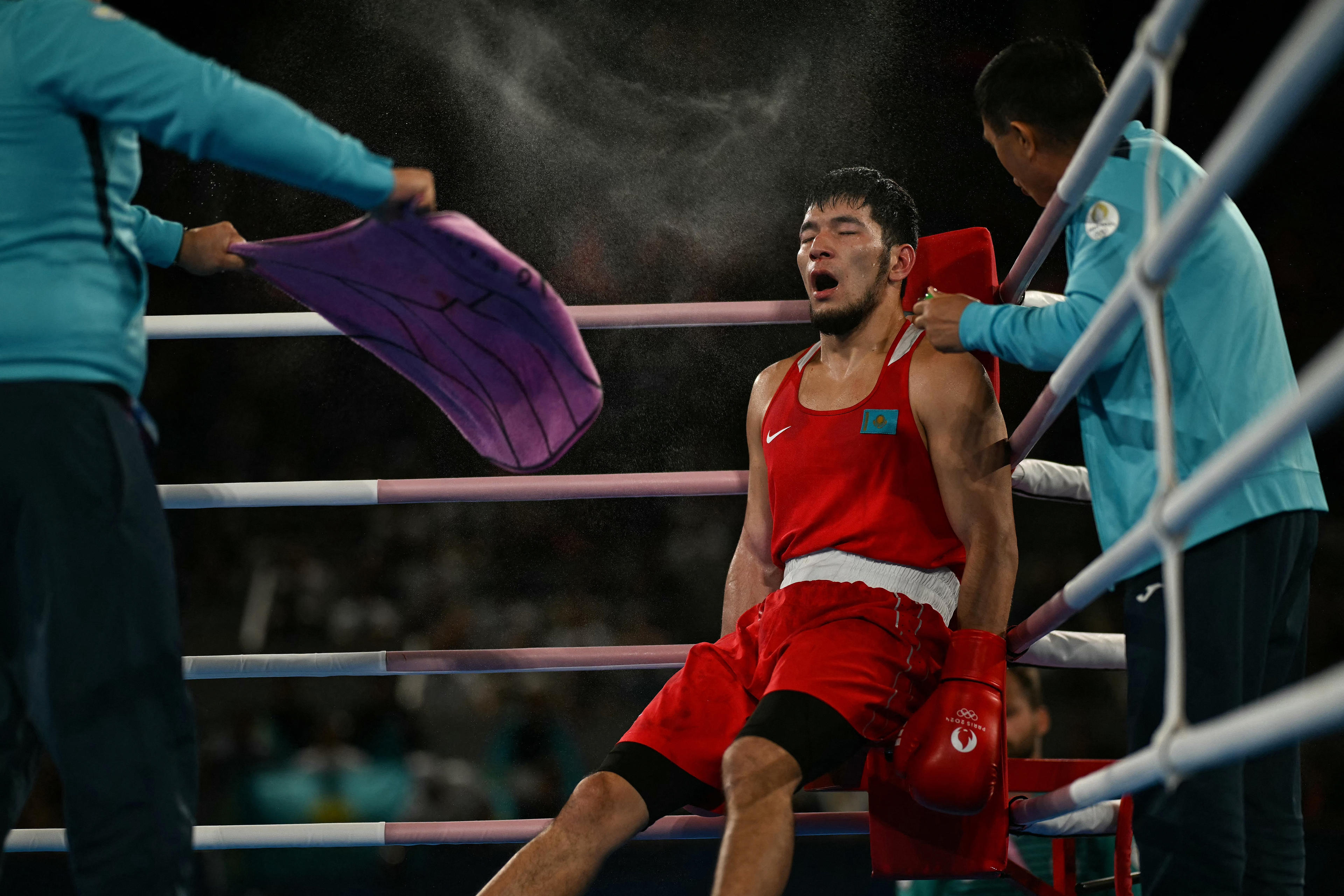 TOPSHOT - Kazakhstan's Nurbek Oralbay receives instructions from the coach during the break while competing against Ukraine's Oleksandr Khyzhniak (Blue) in the men's 80kg final boxing match during the Paris 2024 Olympic Games at the Roland-Garros Stadium, in Paris on August 7, 2024. (Photo by Mauro PIMENTEL / AFP) (Photo by MAURO PIMENTEL/AFP via Getty Images)