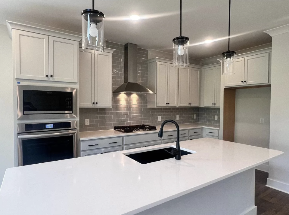 Reddit interior decorating post showing a modern gray kitchen with white countertops and pendant lights. Text: "Warm up a gray kitchen - help!"