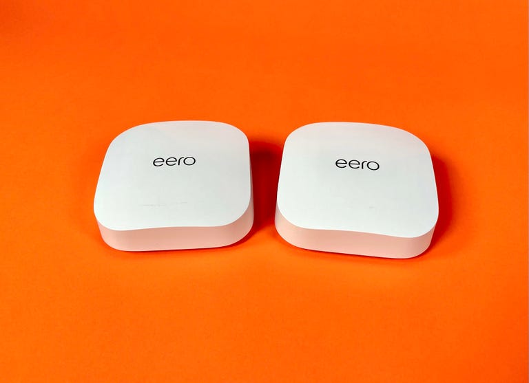 Two Eero Pro 6E mesh router devices sit against an orange background.