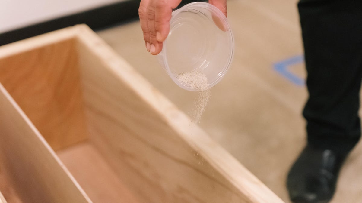 cup of sand being dumped on carpet for test
