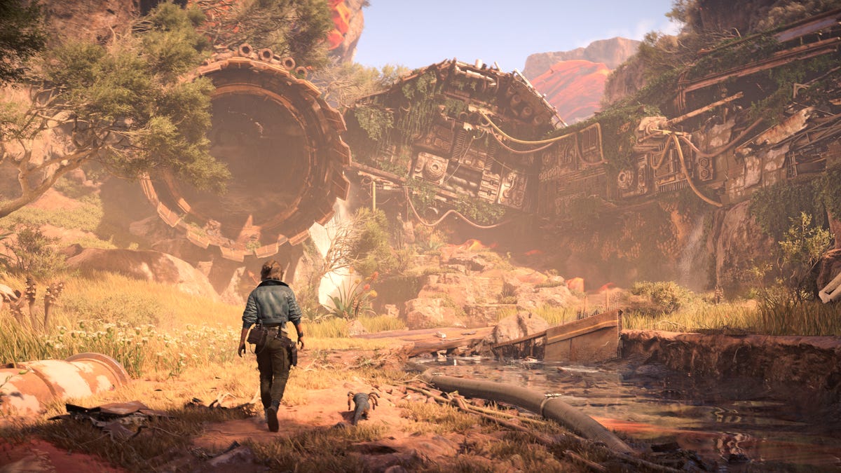 A woman and her alien friend walk in the brush toward a crashed ship long overgrown.