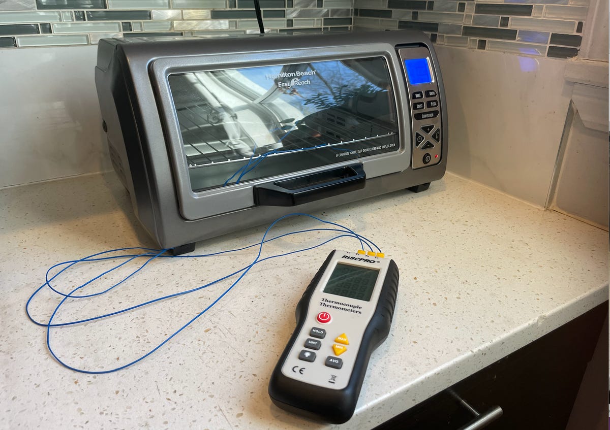 A toaster oven with a digital thermometer hooked up to measure the temperature.