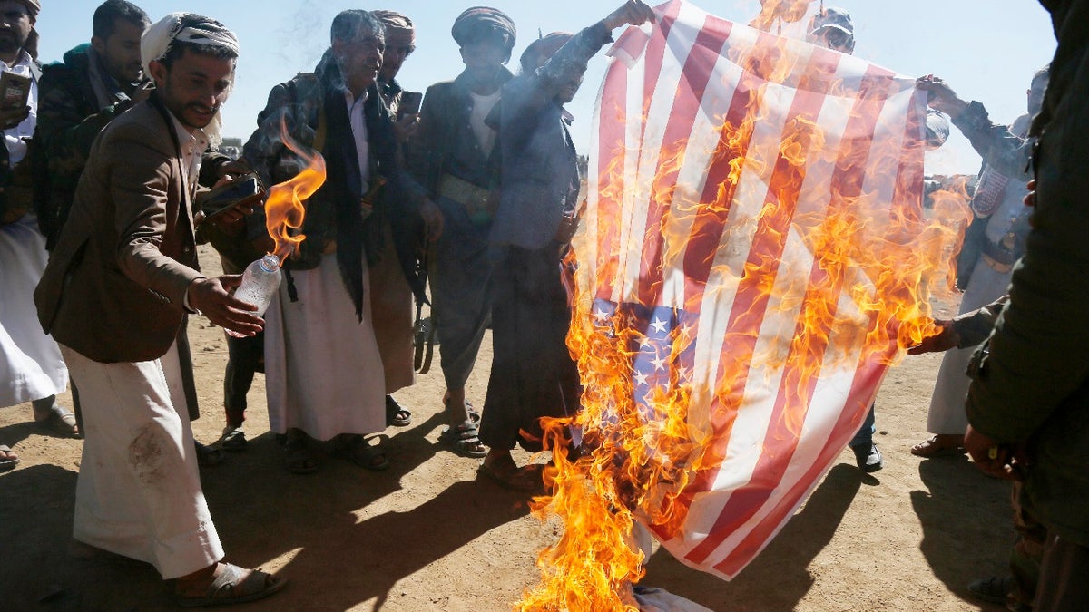 Houthi followers burn the Israeli and American flags during a tribal gathering on January 14, 2024 on the outskirts of Sana'a, Yemen. Houthi followers gathered to protest against the U.S.-U.K. airstrikes on positions in areas under their control.
