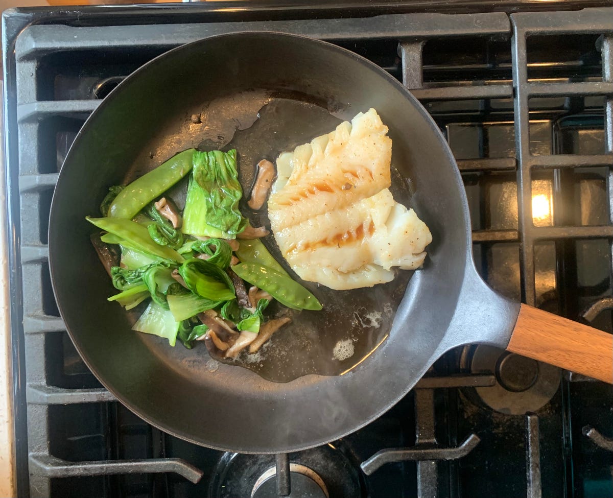 cod in a frying pan with greens.