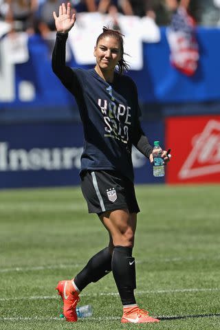 <p>Jonathan Daniel/Getty</p> Hope Solo #1 of the United States waves to the crowd after posting her100th career shut-out against South Africa after a friendly match at Soldier Field on July 9, 2016