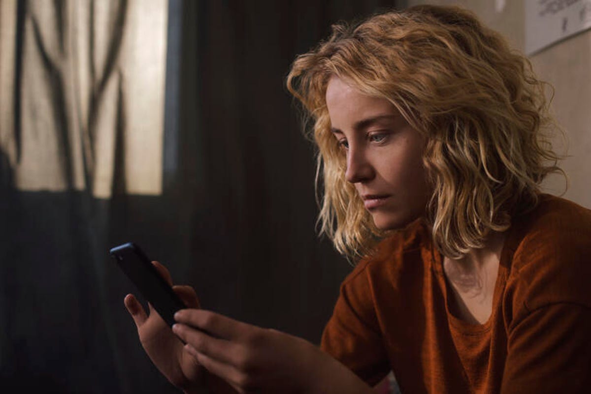 Woman staring at phone in her bedroom