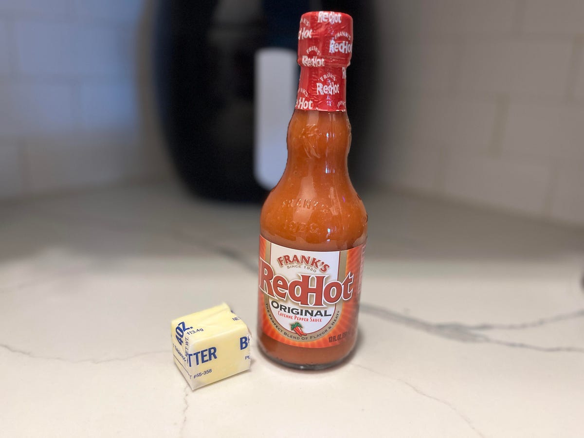 butter and Frank's RedHot hot sauce on a white coutner with an air fryer in the background.