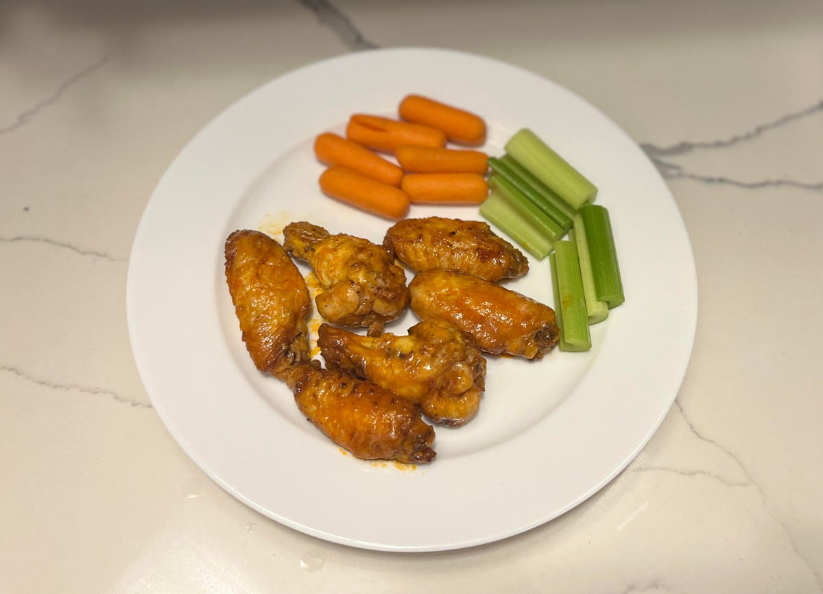 buffalo chicken wings on a white plate with carrots and celery.