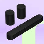 Bundle of three black Sonos speakers including two Era 100 speakers and one Beam soundbar displayed against a lavender background with mint green accents