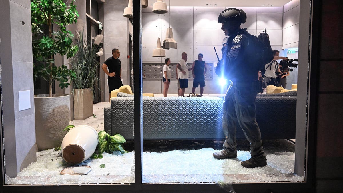 An Israeli police officer inspects the damage to a residential building caused by a rocket fired towards Israel from Lebanon, amid cross-border hostilities between Hezbollah and Israel, in Haifa, Israel, on Oct. 7, 2024.