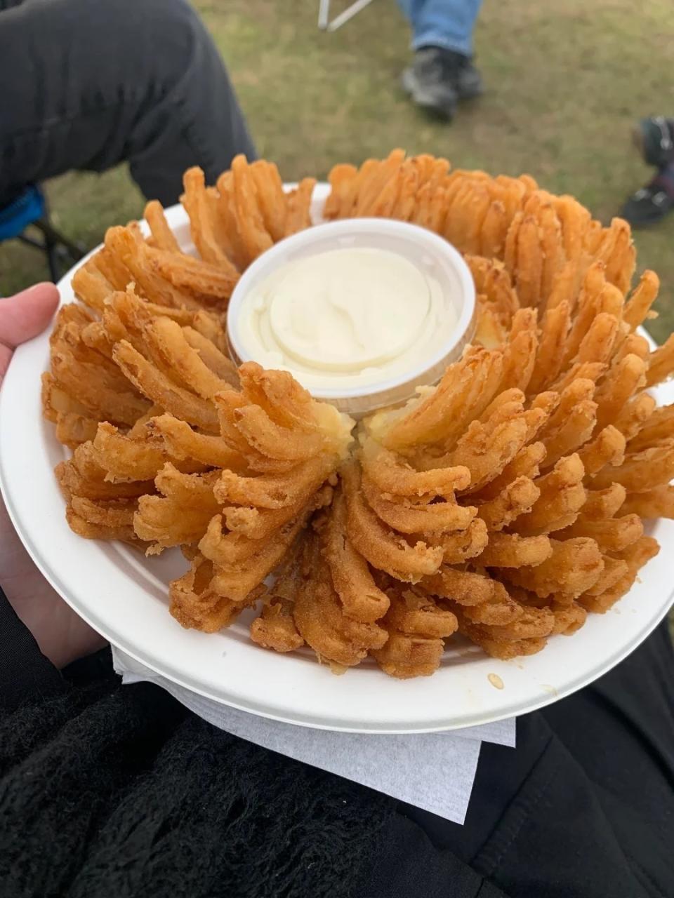 Plate of fried blooming onion with a cup of dipping sauce in the center