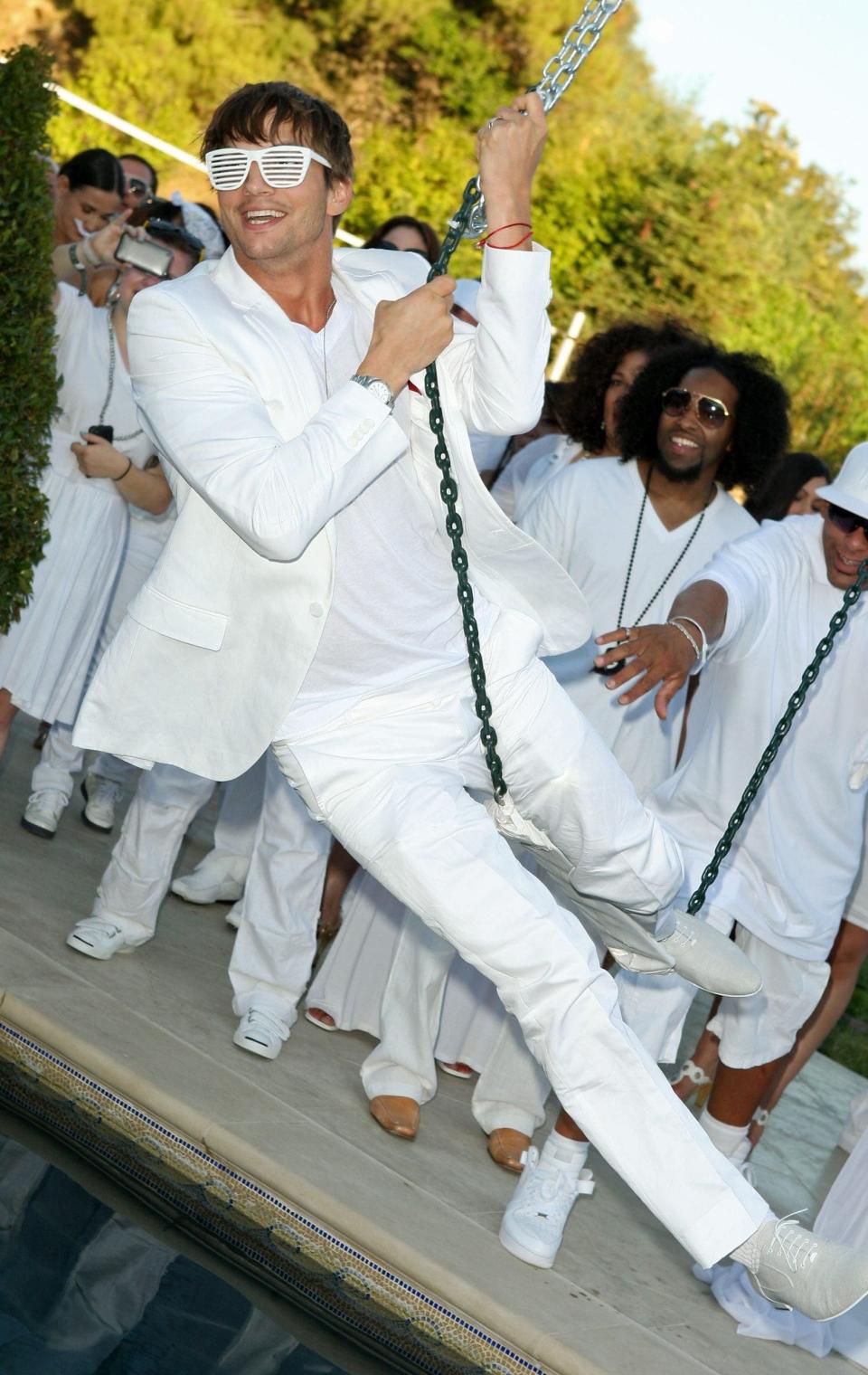 Ashton Kutcher swinging on a swing at the White Party