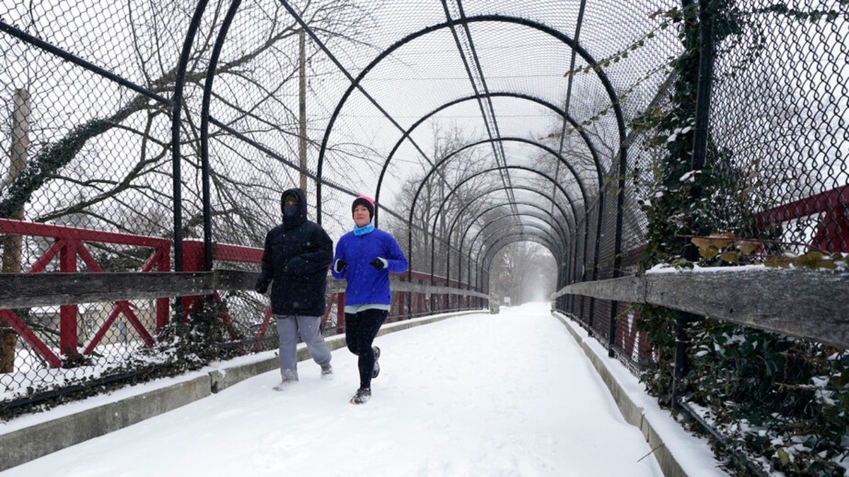 Runners run on a snow covered Monon Trial, Thursday, Feb. 3, 2022, in Indianapolis. A major winter storm with millions of Americans in its path is spreading rain, freezing rain and heavy snow further across the country. (AP Photo/Darron Cummings)