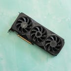 The triple fan side of the RX 7900 XT lying on a marbled green surface