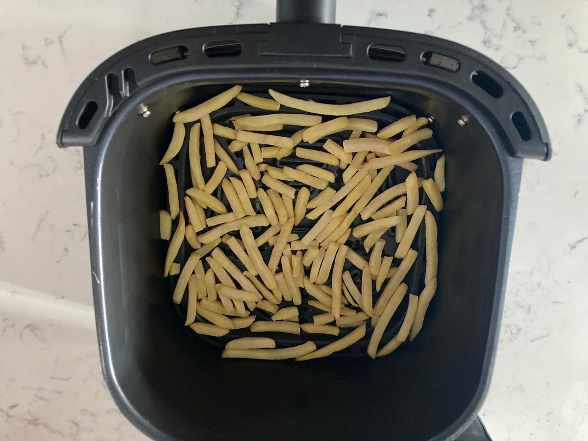 air fryer basket with fries before cooking