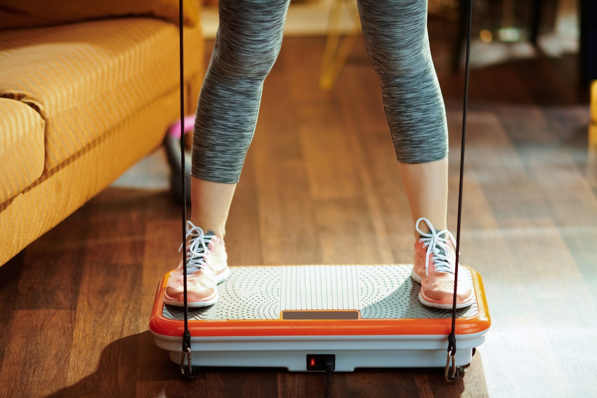 A woman stands on a vibrational plate.