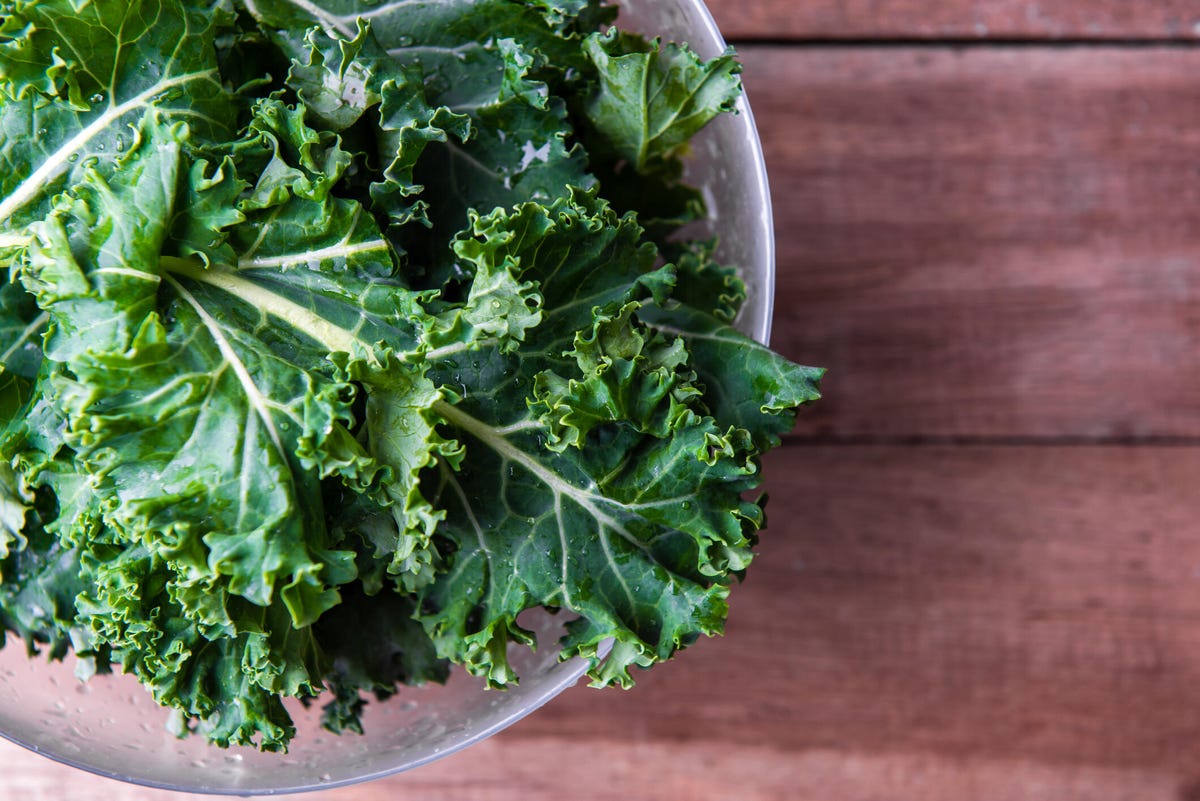 Kale in a bowl on a brown wooden table.