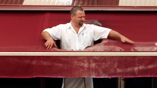 Harry Brosca inspects the damage after a soccer supporter threw a burning flag on top of the Papa Gino’s awning and burnt a hole in 2002.