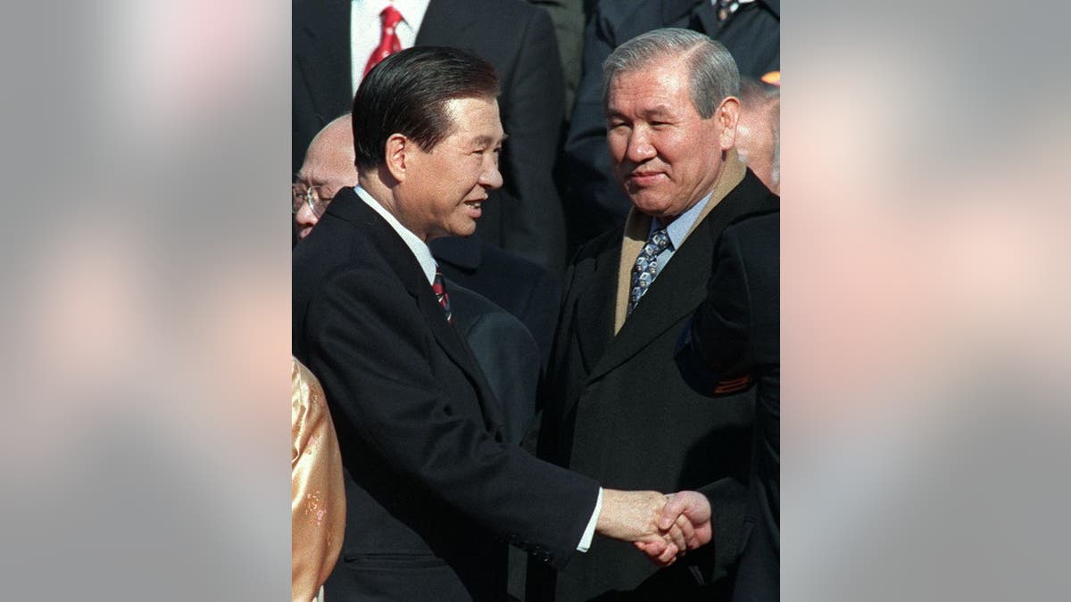Jailed former president Roh Tae-Woo (R) looks on as South Korean new President Kim Dae-Jung (L) shakes hands with jailed former president Chun Doo-Hwan (not in picture) before taking the oath as President during the ceremony of the Inauguration at the National Assembly in Seoul 25 February.