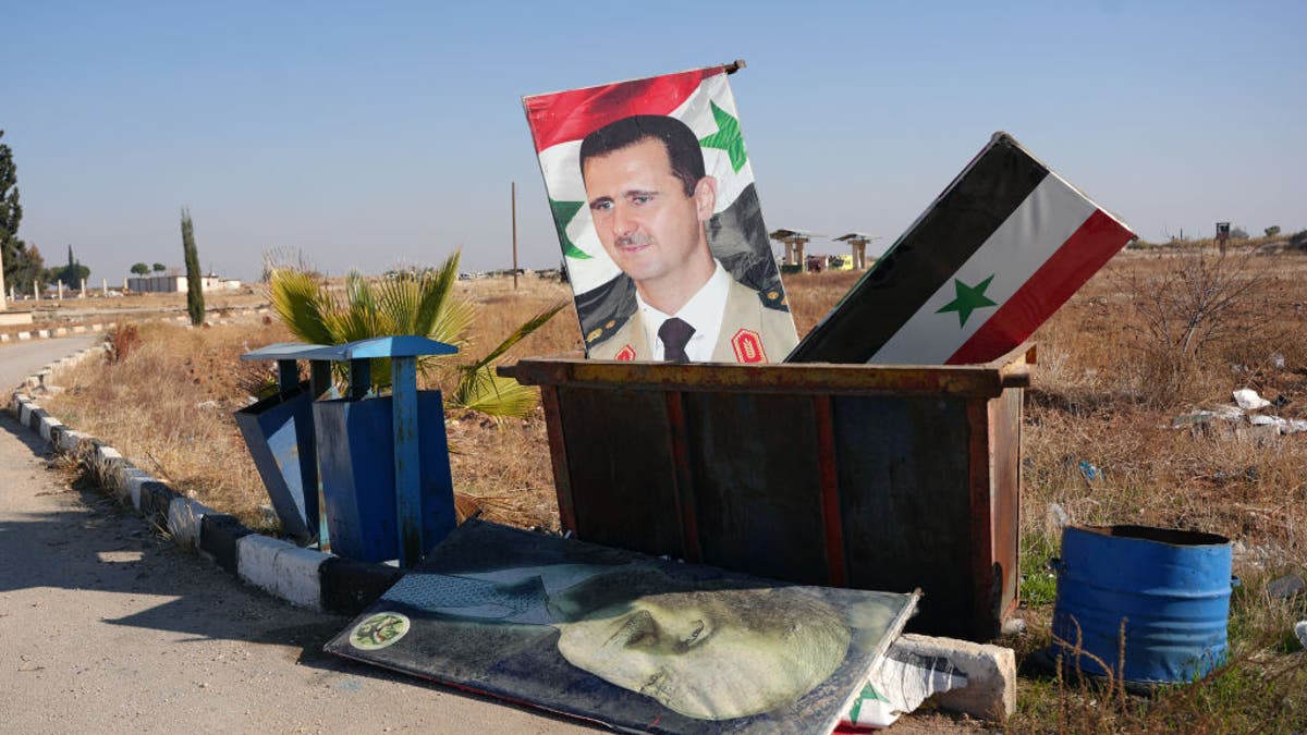 A picture taken at the entrance of the Kweyris military airfield in the eastern part of Aleppo province on Dec. 3, 2024 shows a portrait of Syrian President Bashar al-Assad and a national flag in the garbage dumpster following the take-over of the area by rebel groups.