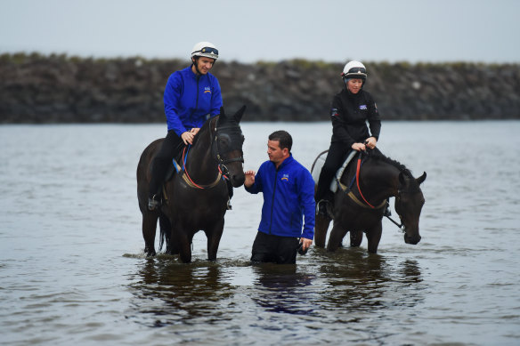 Racehorse Winx (left) is patted by strapper Umut Odemisloglu (centre) as she is ridden at Tower Beach in 2017. The beach is now closed to swimming due to toxic contamination in the area. 